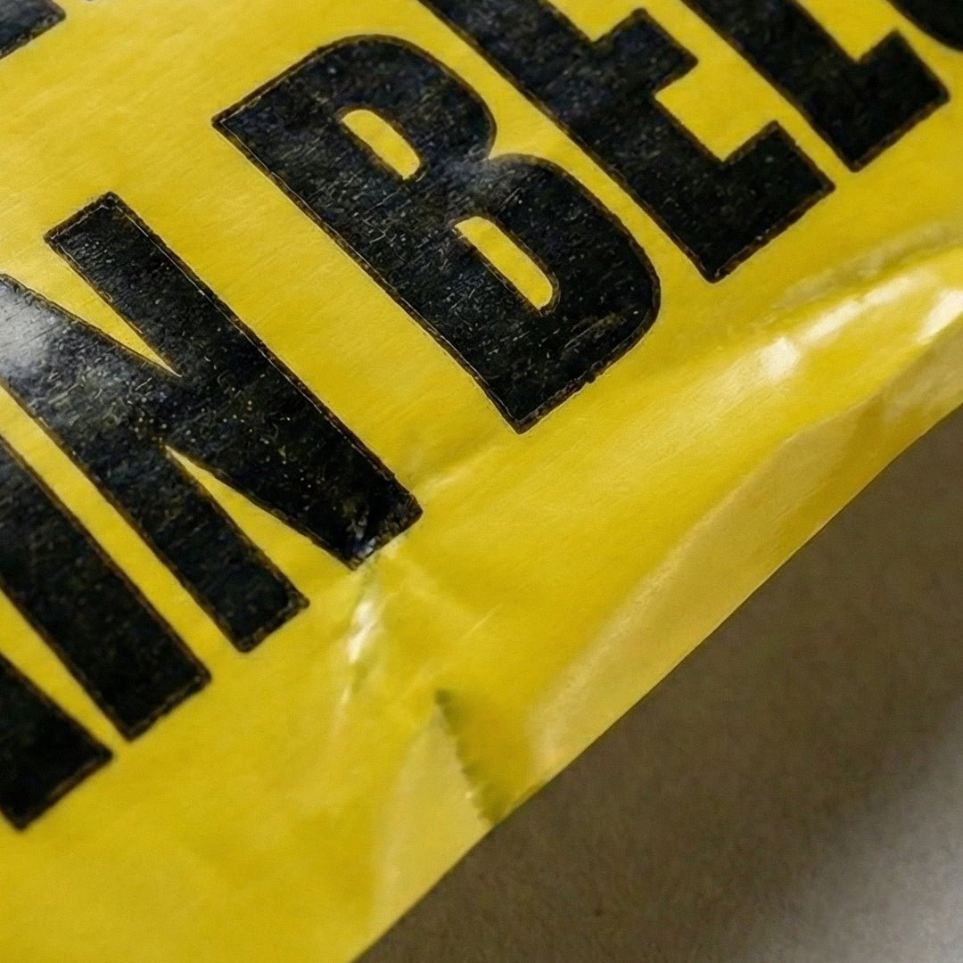 Close-up of a yellow warning sign with black text on a gray background