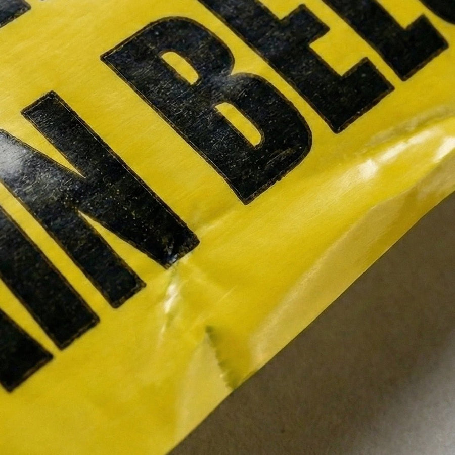 Close-up of a yellow warning sign with black text on a gray background