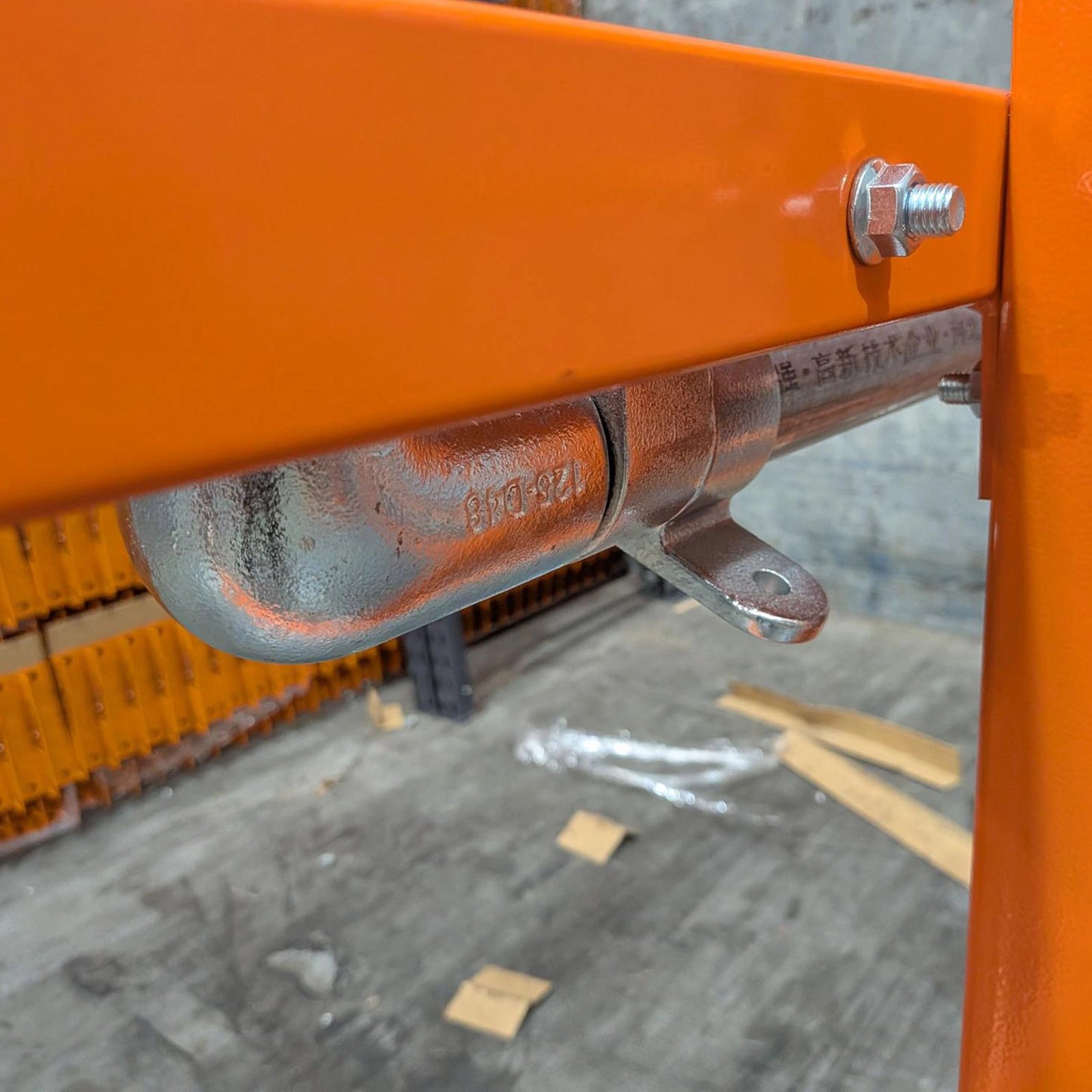 High-visibility orange steel mezzanine up-and-over pallet loading safety gate with gas-assisted pivot arms and an integrated latch mechanism.