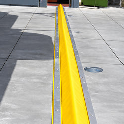 High-visibility yellow PVC-coated foam core drive-over bunding kit laid across a warehouse roller door threshold for spill containment.