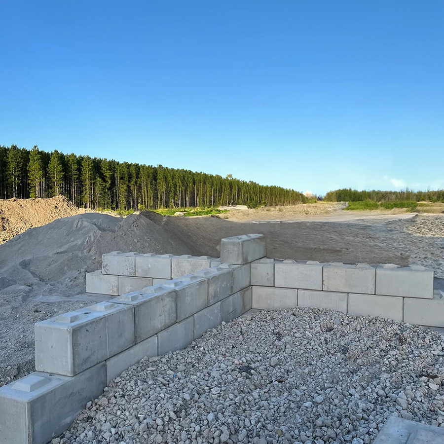 Concrete block foundation in a construction site with trees in the background