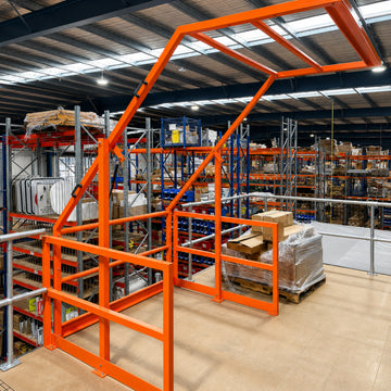 Orange mezzanine up and over safety gate installed on warehouse mezzanine floor